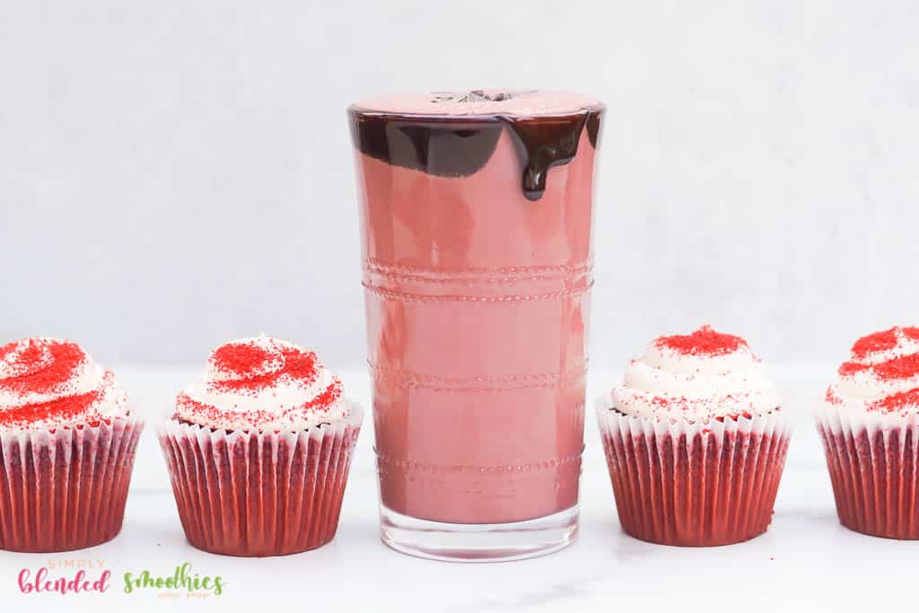 Red Velvet Shake With Chocolate Syrup Dripping Down The Side Chocolate Flakes And Red Velvet Cupcakes On The Side