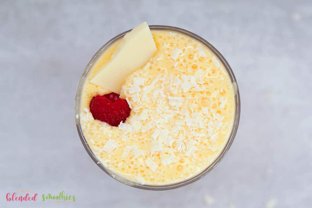 Milkshake Made With Peaches Topped With White Chocolate Shavings And A Raspberry Plus A Chunk Of White Chocolate