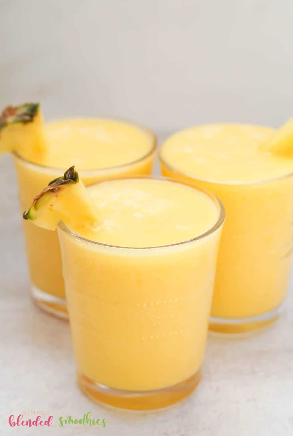 Smoothie Made With Peaches And Pineapple In Clear Glasses With Pineapple Garnish