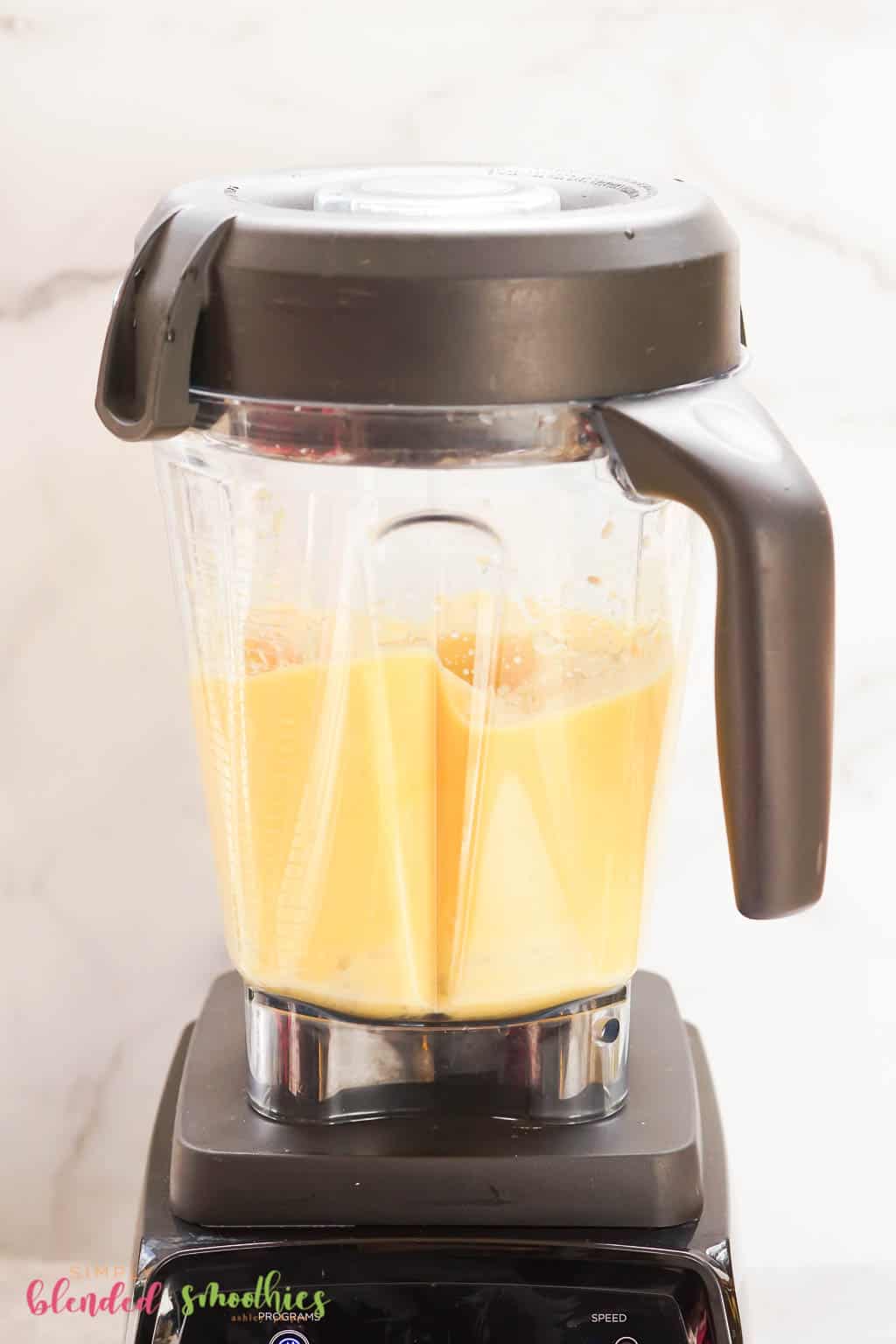 ingredienti per un frullato tropicale che vengono frullati in un mixer